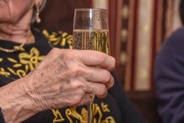 古い女性はシャンパン グラスを手に保持します。 - champagne celebration glass black ストックフォトと画像