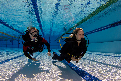 Middle aged Athletes  handsome men scuba divers ready for scuba diving,  jumping in   Beautiful tropical blue sea, coral reef  in the background. Water sports.