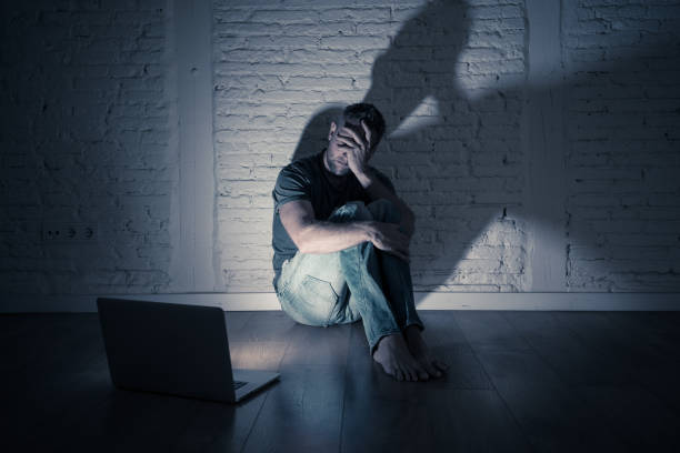 Severely distraught young men with laptop suffering cyberbullying and harassment being online abused by stalker or gossip feeling desperate and humiliated in cyber bullying and social media concept. stock photo