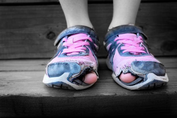 desgastados zapatos viejos con agujeros en los dedos del pie - poverty fotografías e imágenes de stock