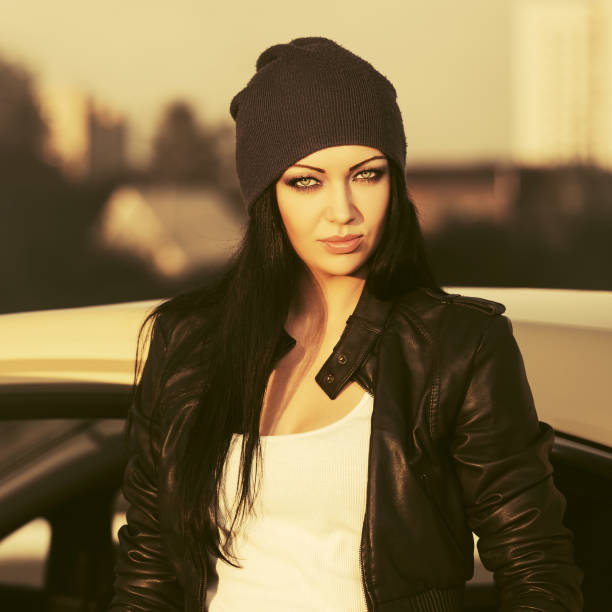 Young fashion woman in leather jacket next to her car stock photo
