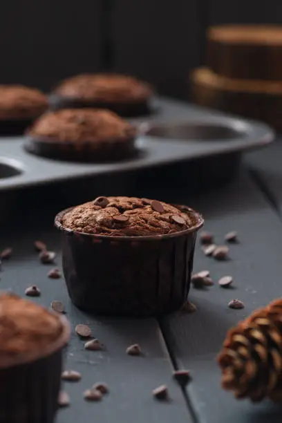 Hygge dessert. Homemade chocolate muffins in baking paper on dark background selective focus