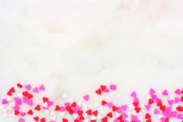 granules valentin coeur fond frontière sur un fond texturé blanc - heart shape stone red ecard photos et images de collection