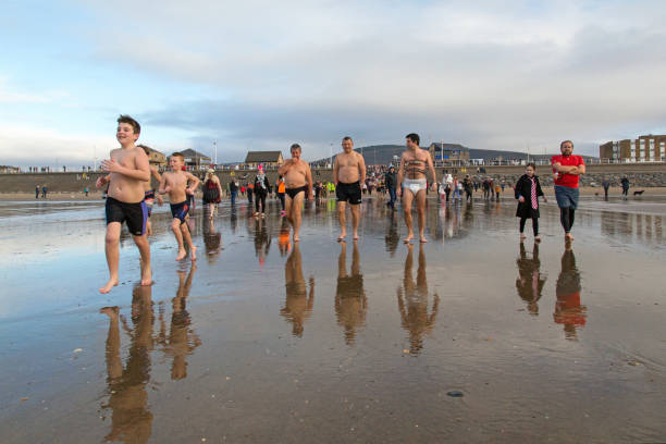 New Year's Day Fancy Dress Swim - UK Aberavon, Wales, UK: January 01, 2019: Children run down the beach towards the sea during a New Year's Day Polar Swim. Some are in fancy dress and any money raised go to a local charity. 2019 new year resolution stock pictures, royalty-free photos & images