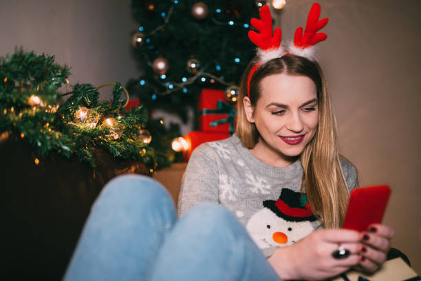istock Charming young woman using smart phone in the Christmas decorated room 1091043272