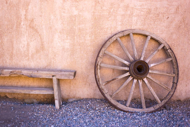 Taos, NM Style: Old Wood Wagon Wheel Against Adobe Wall Taos, NM Style: Old Wood Wagon Wheel Against Adobe Wall. Copy space available. wagon wheel bench stock pictures, royalty-free photos & images
