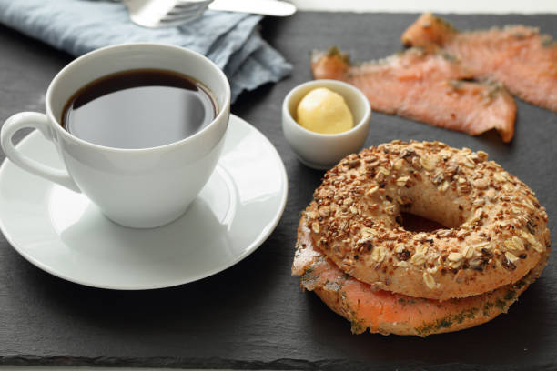 Salmon bagel sandwich and a cup of coffee on a slate cutting board