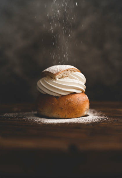 Traditional Swedish dessert Semla with whipped cream and sugar Sprinkling powdered sugar on a traditional Swedish dessert called semlor. sprinkling powdered sugar stock pictures, royalty-free photos & images