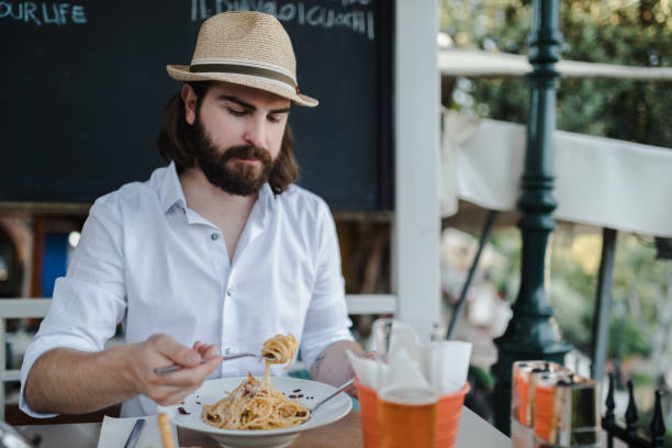 istock Young man eating spaghetti in a restaurant during his vacation 1091066194