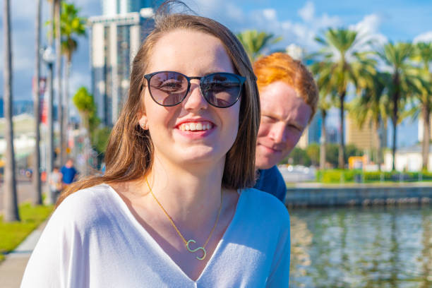 Young Woman Photobombed by Friend A smiling young woman is photobombed by her male friend photo bomb stock pictures, royalty-free photos & images