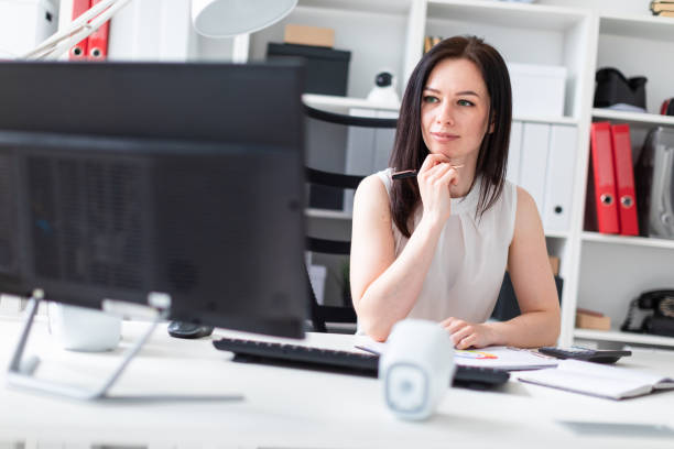 istock A young girl sitting in the office at a computer Desk and working with documents and a calculator. 1091081524