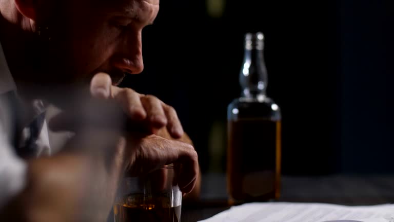 Pensive man leaning hands on glass of whiskey