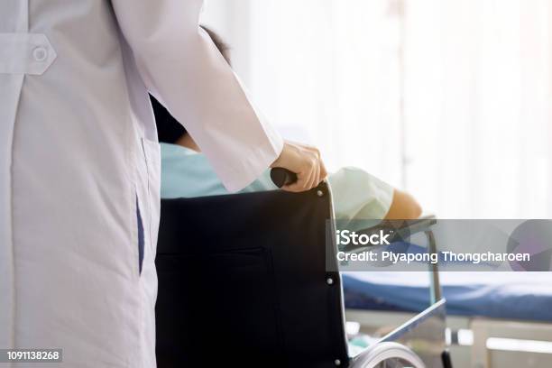 Patient Woman Is Sitting In A Wheelchair With Doctor Standing Behindfocus Hand Stock Photo - Download Image Now