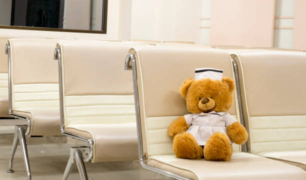 A cute stuffed toy bear dressing in a nurse uniform sitting in the empty hall.