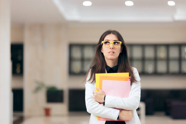 confused businesswoman holding paperwork in office building - biting lip imagens e fotografias de stock