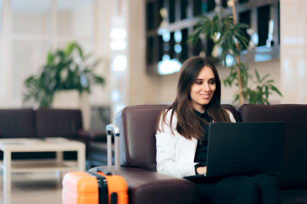 Woman with Laptop and Luggage in Airport Waiting Room Happy businesswoman reading her emails on the go airport departure area stock pictures, royalty-free photos & images