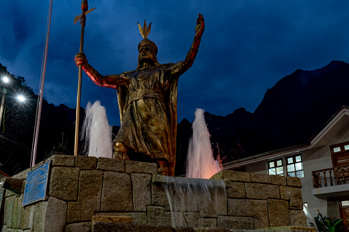 Aguas Calientes, Peru - October 17, 2018: The fountain in the Plaza de armas. Tourists are visiting the street scenery in the evening. Aguas Calientes is the closest town to the ancient Inca city Machu Picchu, it has become a tourist hub for visitors wishing to see the famous landmark.