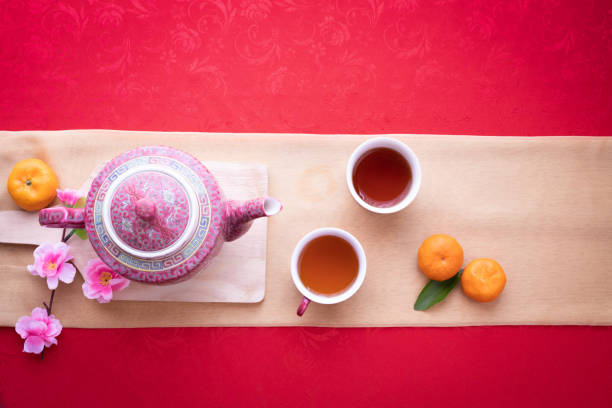 Orange fruit, Pink cherry blossom and teapot with Copy space for text on red texture background, Chinese new year background. top view.