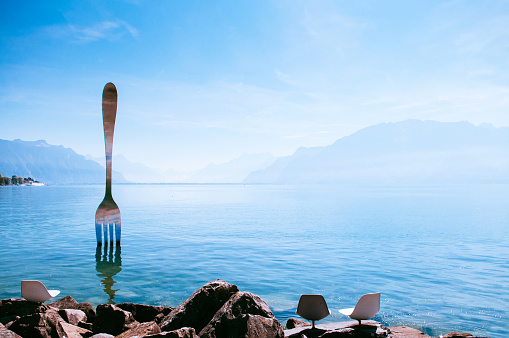 SEP 25, 2013 Vevey, Switzerland - Lake Geneva shore with The Fork of Vevey modern installation art with Swiss alps view on bright sky day in autumn