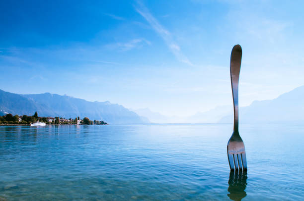 Tourist at Lake Geneva shore with The Fork of Vevey modern installation art SEP 25, 2013 Vevey, Switzerland - Lake Geneva shore with The Fork of Vevey modern installation art with Swiss alps view on bright sky day in autumn montreux photos stock pictures, royalty-free photos & images