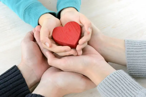 Photo of Heart object covered by family members' hands