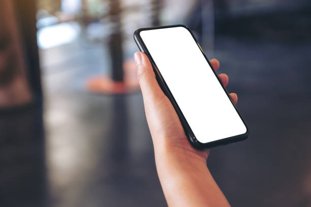 istock Mockup image of a hand holding black mobile phone with blank white desktop screen in cafe 1091187428