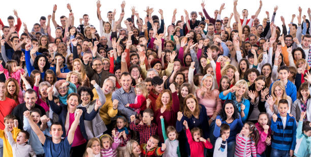 Crowd of excited people celebrating with raised hands. Large group of cheerful people shouting with their arms raised and looking at camera. Isolated on white. cheering group of people success looking at camera stock pictures, royalty-free photos & images