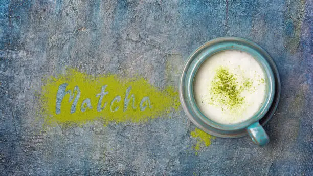 Photo of Top view on lettering from organic green matcha tea powder with popular healthy latte