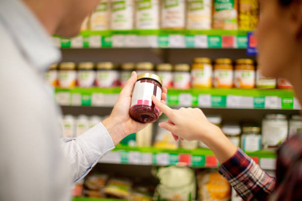 Couple choosing jar of jam Couple choosing jar of marmalade, reading nutrition label nutrition label stock pictures, royalty-free photos & images