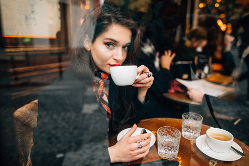 Woman drinking coffee in cafe in Paris, France