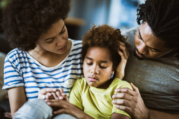 African American parents consoling their sad girl at home. Young black parents taking care of their depressed little daughter at home. woman comforting depressed friend stock pictures, royalty-free photos & images