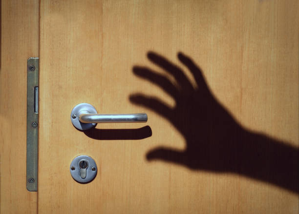 istock shadow of a hand moving towards the doorhandle in torch light 1091225998