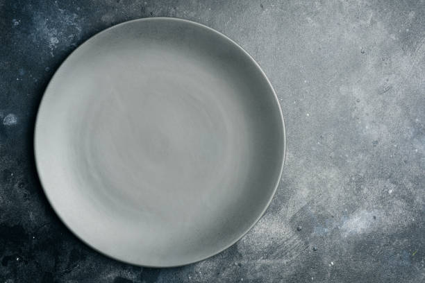 istock Gray empty plate (ceramic) on a gray stone background. Gray minimalism concept. Copy space. 1091227256