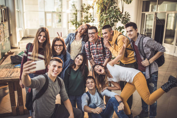 duża grupa szczęśliwych uczniów robi selfie z telefonem komórkowym w szkole. - mobile phone group of people photographing teenager zdjęcia i obrazy z banku zdjęć