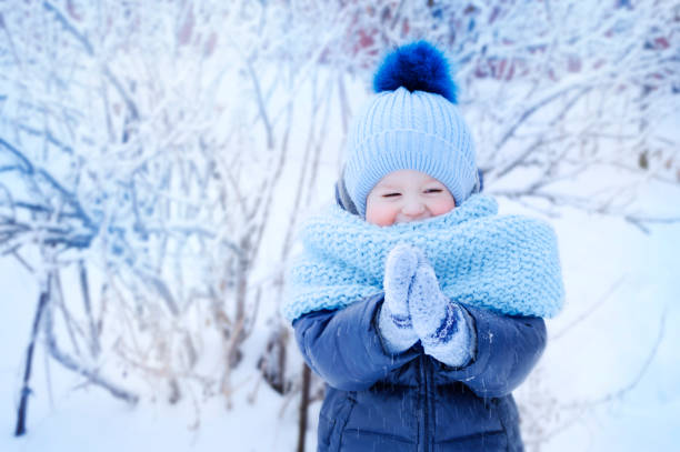 retrato de un niño en ropa de invierno azul en un paseo por el parque en invierno - mejillas enrojecidas fotografías e imágenes de stock