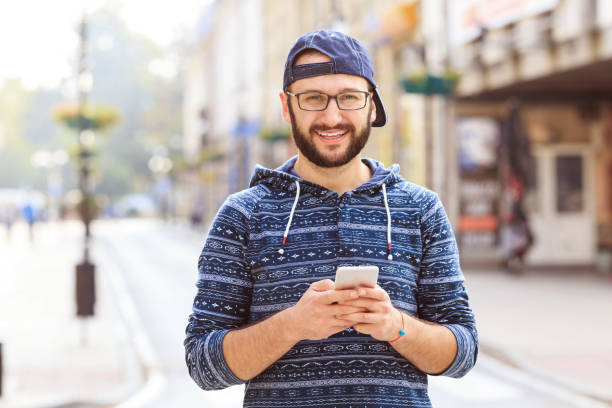 istock Smiling man with smart phone on city street 1091234400