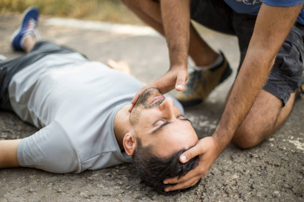 Man gives first aid to a person on the asphalt stock photo