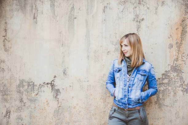 istock Young beautiful woman with denim jacket standing on a rusted wall 1091236668