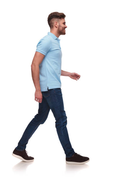 side view of casual man in blue polo shirt walking side view of casual man in blue polo shirt walking on white background and smiling, full body picture side view stock pictures, royalty-free photos & images
