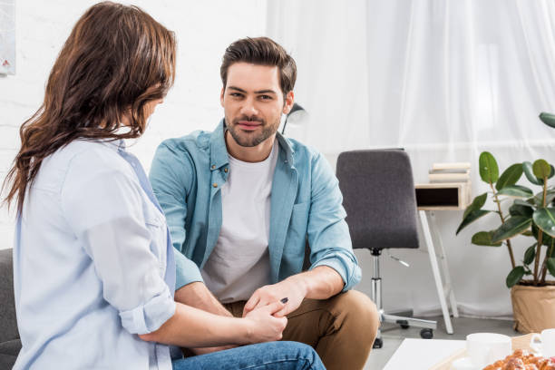 istock couple sitting on couch and holding hands while man looking at camera at home 1091246194