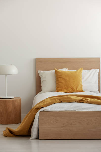 cuscino giallo e coperta su biancheria da letto bianca in semplice camera d'albergo con letto singolo, spazio di copia su parete vuota - hotel room hotel bed bedroom foto e immagini stock