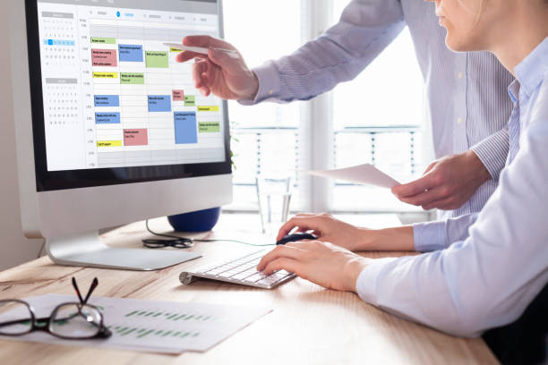 istock Colleagues planning a meeting with calendar software on computer, search time slot between events, tasks, and appointments, busy business people using time management tool to organize work, office 1091264650