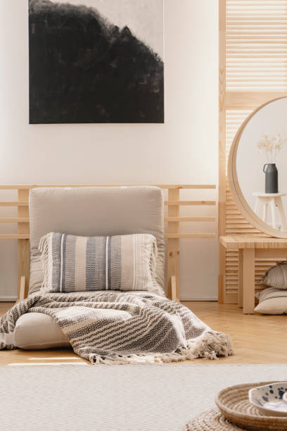 istock Vertical view of black and white abstract painting above white warm blanket and patterned pillow on beige futon in elegant natural bedroom interior, real photo with mockup on the empty wall 1091279276