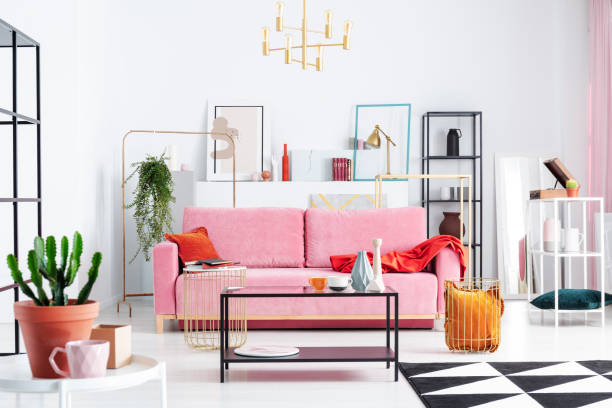 istock Patterned carpet and pink couch in white apartment interior with posters and lamp above table. Real photo 1091285476