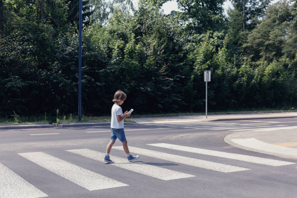 istock Boy crossing the street while looking at his smartphone 1091286592
