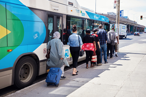 Montreal, Canada - June, 2018: People waiting in queue on the public bus station to get on the bus in Montreal, Quebec, Canada. Editorial use.