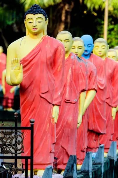 Statues of monks standing in a row behind the Buddha in one of the temples of Sri Lanka.