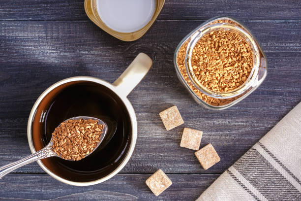 Instant coffee. Cup with hot water and instant coffee spoon on wooden table. Instant coffee. Cup with hot water and instant coffee spoon on wooden table. Top view. instant coffee stock pictures, royalty-free photos & images