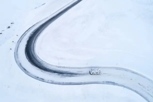 Aerial view of motor home driving over winding, almost completely snow covered Julier Pass in Switzerland, a lot of copy space.