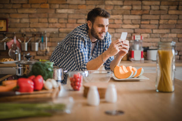 istock Happy man reading recipes on cell phone in the kitchen. 1091302804